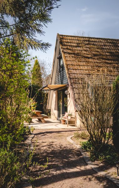 Woning met steile daklijn naast een tuinpad